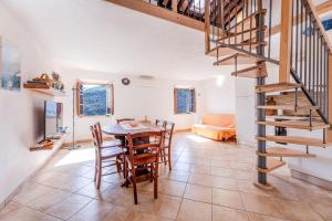 a kitchen and dining room with a table and a spiral staircase at La Fortezza - Goelba in Marciana