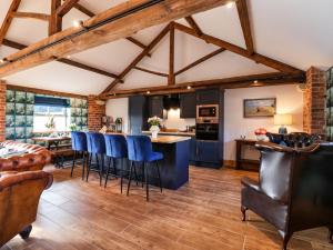 a kitchen and living room with wooden ceilings and blue chairs at Beth's Cottage in Malton