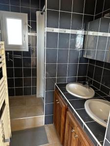 ein schwarz gefliestes Bad mit einem Waschbecken und einem Spiegel in der Unterkunft Marina 4 adultes 4 enfants piscine commune in Aigues-Mortes