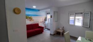 a living room with a red couch and a table at El Rinconcito Cubano en la playa in Almería