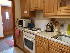 a kitchen with a stove top oven next to a sink at Shire Cottage Devils Bridge in Yspytty Cynfyn