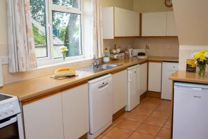a kitchen with white cabinets and a sink and a window at Soar Cottage Aberystwyth in Aberystwyth +11 photos