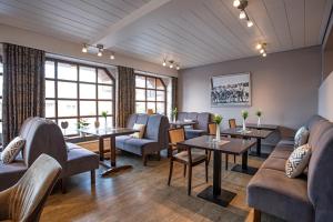 a waiting room with tables and chairs and windows at Lieblingsplatz Hotel Seedeich in Grömitz