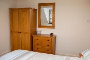 a bedroom with a wooden dresser and a mirror at Townhouse Aberystwyth in Aberystwyth