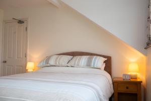 a bedroom with a bed with white sheets and two lamps at Townhouse Aberystwyth in Aberystwyth