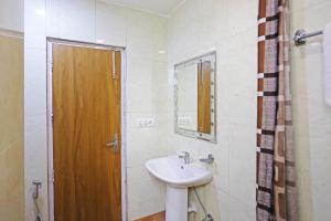 a bathroom with a sink and a wooden door at Frankstay by Hotel Satwah 29 Unit By Preet Palac in New Delhi