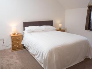 a bedroom with a large white bed with two night stands at Ty Ceiniog New Quay in Cross Inn