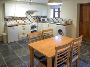 a kitchen with a wooden table and chairs at Ty Ceiniog New Quay in Cross Inn