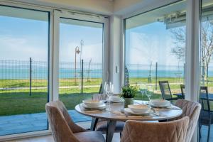 jadalnia ze stołem i krzesłami oraz dużymi oknami w obiekcie MF Sunset Beach77 Premium Apartment w Siófoku