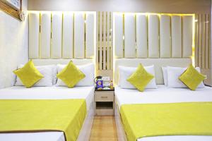 two beds in a hotel room with yellow and white pillows at Frankstay by Hotel Satwah 29 Unit By Preet Palac in New Delhi
