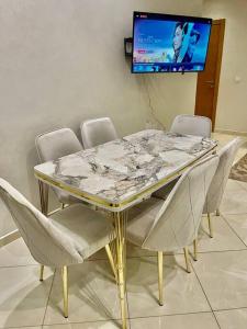 mesa de comedor con sillas y TV en la pared en Luxurious 2 BD apartment in the Heart of Kenitra, en Kenitra