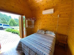 グラマドにあるCabanas Encantos da Naturezaの木造キャビン内のベッド1台が備わるベッドルーム1室を利用します。