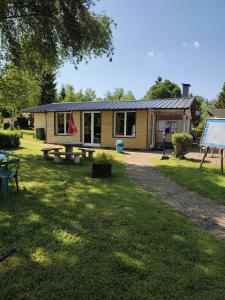 une maison avec une table de pique-nique dans l'herbe dans l'établissement Camping la Vallée, à La Tour-dʼAuvergne