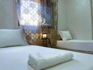 a bed with a white blanket on it with a lamp at شقه معاصره ب لمسة مغربيه في فاس in Fès
