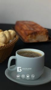 a cup of coffee on a plate next to a basket of bread at Gran Lord Hotel in Pará de Minas