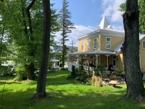 una casa amarilla con un patio con árboles en Gîte au Charme Victorien en Beauceville