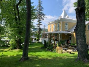 a yellow house with a yard with trees at Gîte au Charme Victorien in Beauceville