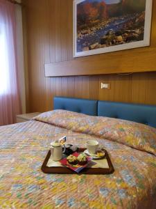 カステッロ・テジーノにあるAlbergo Bellavistaのベッドの上にトレイ(食べ物、飲み物付)