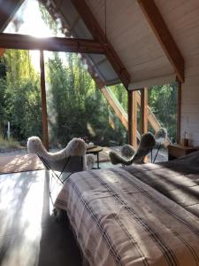 a bed in a room with a large window at El Diucón Eco Lodge in Villa Meliquina