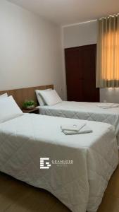 2 łóżka w pokoju hotelowym obok siebie w obiekcie Gran Lord Hotel w mieście Pará de Minas