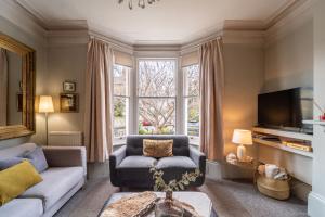 a living room with a couch and a tv at Victorian Townhouse 5 bedrooms Cheltenham in Cheltenham