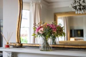 a vase of flowers on a table in front of a mirror at Victorian Townhouse 5 bedrooms Cheltenham in Cheltenham