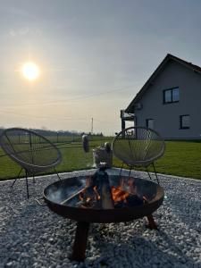 a fire pit with two chairs around it with the sunset at Lamelove Apartments in Chocznia