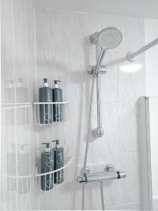 une salle de bain avec une douche avec quatre bouteilles au mur dans l'établissement Deluxe 2-bed apartment with free parking, netflix & fast WiFi, à Farnworth