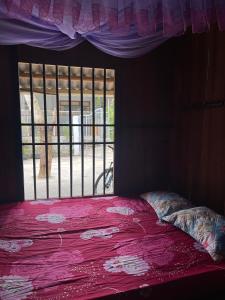 a bedroom with a pink bed with a window at Homestay Nature in Na Hang
