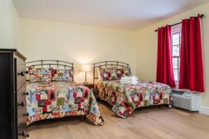 two beds in a room with red curtains at Spruceholme Inn in Fort Coulonge