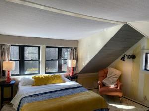 a bedroom with a bed and a chair and windows at The Four Pillars Farmstead 