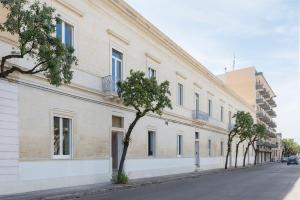 un edificio blanco con árboles al lado de una calle en Palazzo Ricciardi Residence, en Lecce