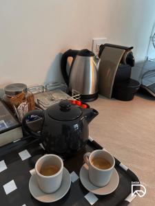 dzbanek do herbaty i dwie filiżanki kawy na stole w obiekcie DADA Home w mieście Bari