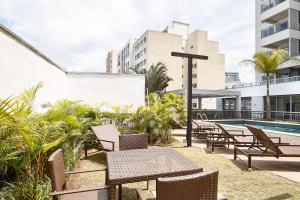 Apartamentos completos em Pinheiros a uma quadra da Faria Lima - HomeLike في ساو باولو: فناء به طاولات وكراسي بجانب مسبح