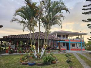 a house with two palm trees in front of it at Acogedor alojamiento rural in Filandia