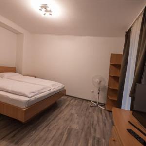 a bedroom with a bed and a wooden floor at Kikötő Anna Apartmanok in Balatonboglár