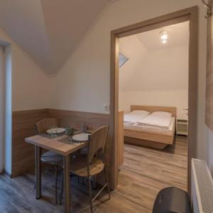 a room with a table and a bedroom with a bed at Kikötő Anna Apartmanok in Balatonboglár