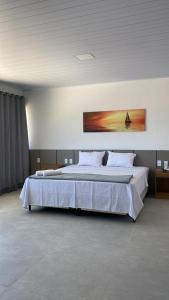 een slaapkamer met een groot bed met witte lakens bij Pousada Cantinho da Barra in Barra de São Miguel