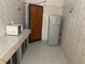 a small kitchen with a microwave and a refrigerator at Appartement chambre 2 in Dakar