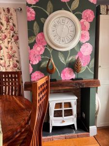 a clock on a wall with pink flowers at The Garden Annexe in Longhope