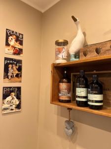 a shelf with bottles of whiskey and a vase on it at The Garden Annexe in Longhope