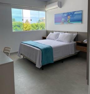 een slaapkamer met een bed en een groot raam bij Pousada Cantinho da Barra in Barra de São Miguel
