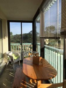 a living room with a wooden table and a balcony at Location 1 à 4 pers. dans résidence Front de mer in Soulac-sur-Mer +18 photos