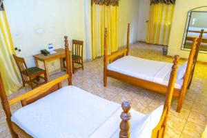 a room with three beds and a table and a desk at Nv Fort Lugard Hotel Iganga in Iganga