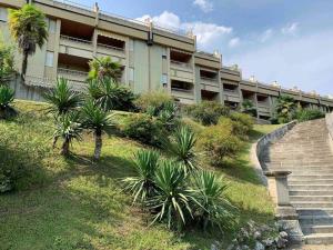 a building with stairs and palm trees in front of it at Ferienwohnung Studio Bella Verde in Lesa