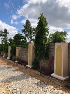 a brick fence with trees and trees behind it at VILLA ESPERANZA KITUI in Kitui