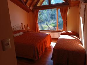 a bedroom with two beds and a large window at Hostería Rutalsur in Tolhuin