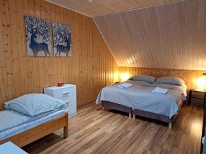 1 dormitorio con 2 camas en una habitación con paredes de madera en Noclegi Pod Modrzewiem en Powidz