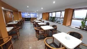 a dining room with tables and chairs and windows at César Inn Juiz de Fora Hotel in Juiz de Fora