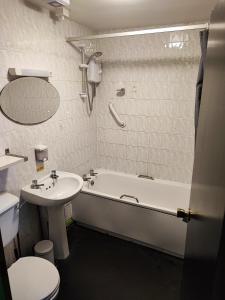 uma casa de banho com um lavatório, uma banheira e um WC. em Happy Guests Lodge em Lower Whitley